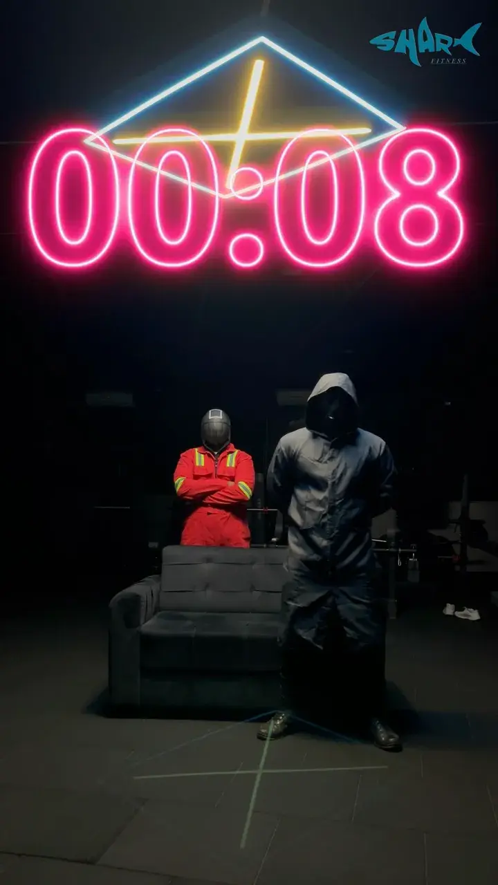The neon countdown at 00:08 above two masked figures, one in red, beside a sofa