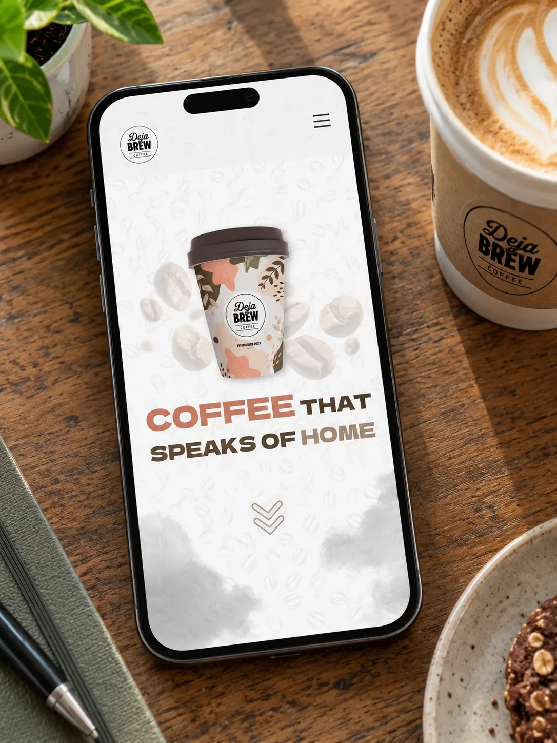 A phone on a café table showing the Deja Brew mobile home page, next to a takeaway cup.